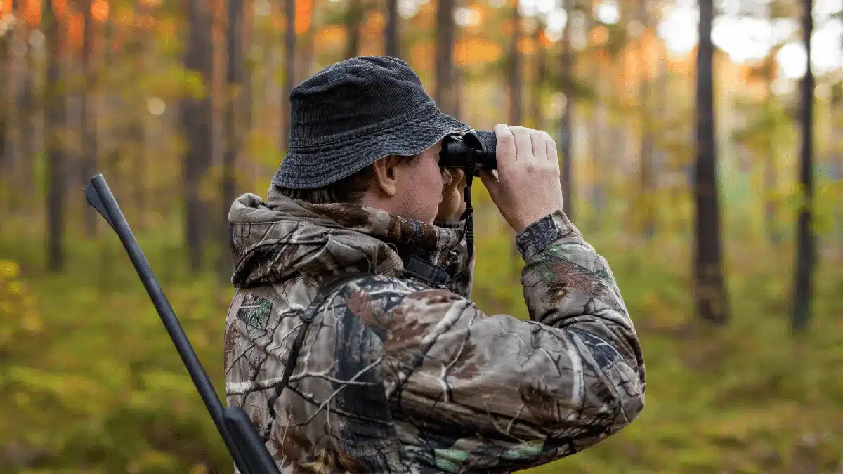 Hunter using binoculars in camouflage gear for hunting marketing strategy
